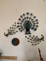 Full display of the four peacock-themed wall decorations arranged on a wall.