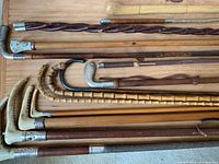 Overhead view of multiple walking sticks and riding crops on wooden surface