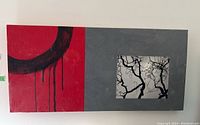 Front view of the rectangular wall art with red and gray background, black circular brushstroke and tree branch motif, mounted on wall.