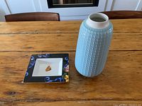 Photo showing light blue ceramic vase next to Lenox porcelain dish on wooden table
