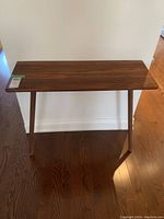 Front view of the hardwood console table with two legs, wall-mounted, showing tabletop surface and wood grain.