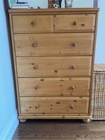Front view of wood dresser with five drawers, natural finish, rounded wooden knobs, and scratches.