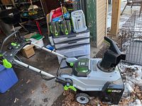 Side profile of snowblower with handle folded and accessories stacked behind