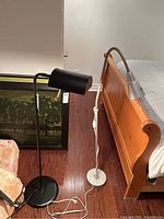 View showing both floor lamps near a bed, highlighting metal constructions and size comparison