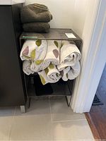 Overall view of the metal mesh storage shelf with towels stacked and rolled on shelves.