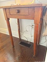 Front angle view of wooden side table showing front drawer and legs.