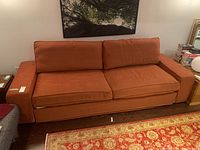 Front view of rust orange fabric sofa with cushions in living room