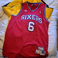 Full view of the red Julius Erving Philadelphia 76ers basketball jersey with the track suit jacket beneath it.