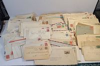 Photo showing a broad view of the first day letters collection, featuring multiple envelopes stacked and spread showing stamps and addresses.