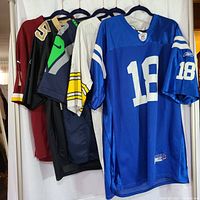 Five NFL jerseys hanging on hangers showing the full front sides and part of sleeves