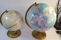 Two vintage globes on stands, different sizes and styles visible