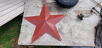 Single photo showing a 17-inch metal star with a reddish finish placed on a surface next to some tools and a tire, likely for scale and context.