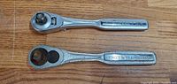 Two Craftsman ratchet wrenches placed on a wooden surface showing both top and handle with logo and forging details