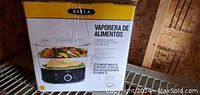 Photo of the BELLA food steamer box showing the product image and Spanish product description on front side.