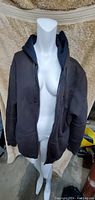 Front view of brown Under Armor men's hooded jacket on a mannequin, showing front zipper, hood, and pockets.