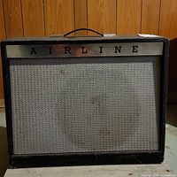 Front view of amplifier showing metal 'AIRLINE' logo on silver panel, grey woven grille cloth and black tolex covering with top handle