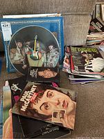 Photo showing Beatles picture disc clocks, several Beatles books including John Lennon and Paul McCartney biographies, and stacked magazines and newspaper articles.