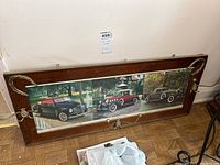 Full view of coat rack showing wood frame, vintage car collage, and four metal double hooks.