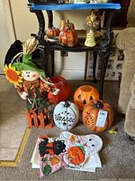 Table with various fall and Halloween decorations including scarecrow, pumpkins, and Halloween-themed hand towels