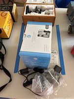 Top view of AT&T cordless phone box with charger adapters and cords alongside.