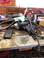 Photo shows several power tools piled on a workbench including a calculator, various cords, and the tools described by seller.