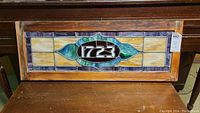 Full view of stained glass panel with 1723 center in wood frame