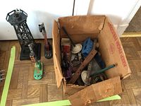 Overview of garden train parts including a cardboard box filled with various metal components and two metal towers.