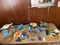 Overview of multiple Star Trek model starships, accessories, game, and parts spread on two wooden tables against a wood-paneled wall