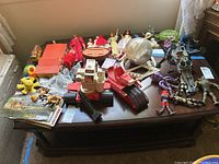 Overview of lot showing space playset, action figures, dolls, vehicle, horse and soldier figurines, baby toys