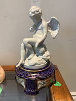 Full view of white ceramic angel figurine on an ornate blue porcelain base showing details of angel and base