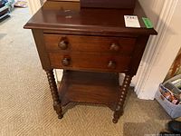 Front view of walnut antique side table showing two drawers with round wooden knobs and turned legs.