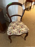 Photo of balloon back chair front view showing floral upholstered seat and wooden frame with curved back and cabriole legs.