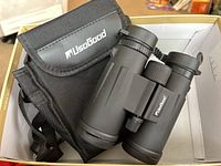 Binoculars with carrying case inside a box, shows Usogood branding on case and binoculars.