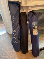 Three folded camp chairs standing upright in their storage bags