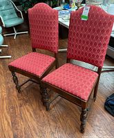 Two wood frame chairs with padded backs and red diamond-pattern fabric upholstery shown side by side from the front.