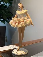Front view of porcelain ballerina figurine showing detailed face, pink tutu with lace, and standing pose.