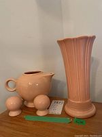 Photo showing all four Fiesta pottery pieces: vase, jug, and two salt and pepper shakers on wooden surface against wall.
