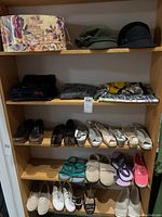 Photo showing shelf with 2 wool hats, multiple scarfs, 13 pairs of women's shoes size 9.5, and floral decorative hat box.