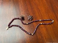 Full lot view showing the ring, brooch, and necklace on wooden surface