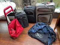 Full view of all five items: three rolling cases, red shopping trolley, blue sport duffel bag