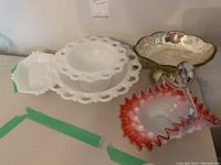 Overview of milk glass bowls, tray, and art glass bowls on table