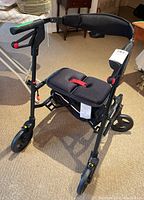 Front-side view of the black Nexus folding walker showing handbrakes on handles, padded seat, handbrake cables, and front wheels.