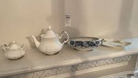 Wide view of Royal Albert Chantilly white porcelain teapot and sugar bowl alongside Limoges and Dalehall serving pieces on display surface