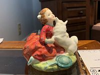 Front view of figurine showing girl in red dress with dog embracing