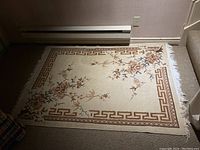 Top view of one floral pattern rug with cream background, brown geometric border, and floral branch motifs.