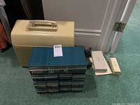 Overall lot showing Kenmore sewing machine case, blue organizer, and boxed attachments plus paperwork on carpet.