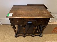Front angle view of the wooden side table showing the top surface and three drawers.