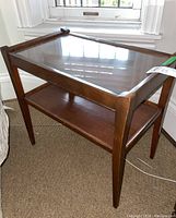Photo showing the side table with glass top, angled front view, highlighting the glass insert and wooden frame.