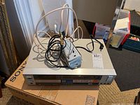 Sony TC-FX66 tape recorder atop a Sony CD player box with attached cables and remote control.