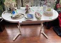 Front view of rectangular table showing composite surface and metal legs with items on top (not included).